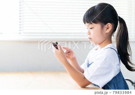部屋でスマホを使う小学生の女の子 部屋でスマホを使う小学生の女の子 79833984