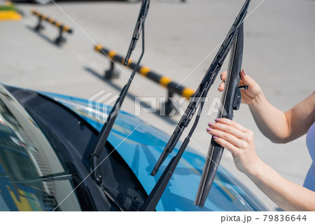 Faceless woman changing car windshield wipers. 79836644
