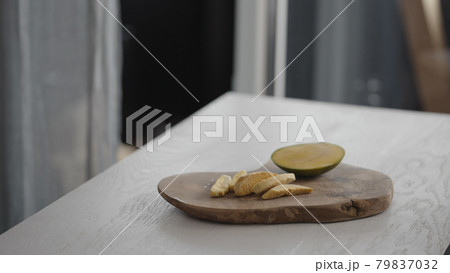 Sublimated mango next to fresh mango on olive board on white oak table 79837032