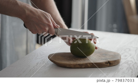 Man cutting ripe mango on olive board on white oak table Man cutting ripe mango on olive board on white oak table 79837033