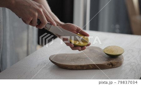 Man cutting ripe mango on olive board on white oak table Man cutting ripe mango on olive board on white oak table 79837034