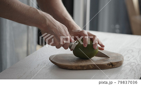 Man cutting ripe mango on olive board on white oak table Man cutting ripe mango on olive board on white oak table 79837036