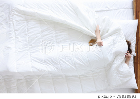 Drunk woman lies with bottle of alcohol in bed closeup 79838993