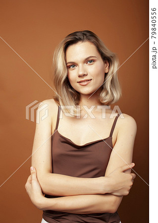 young pretty girl with blond hair posing cheerful on brown background, lifestyle people concept 79840556
