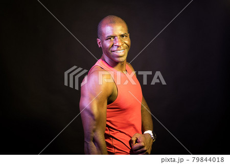 Portrait of an African American man wearing tank top standing looking at camera. Portrait of an African American man wearing tank top standing looking at camera. 79844018
