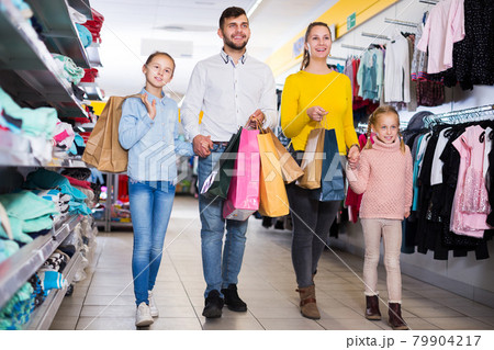family of four with shopping bags walking 79904217