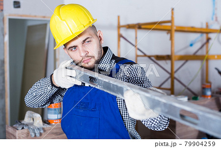 Repairman in helmet is looking at the level of the profile 79904259
