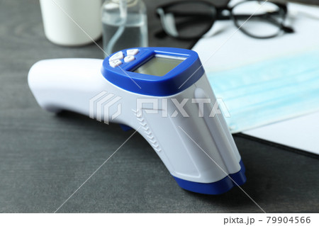 Medical tools and thermometer gun on dark wooden background Medical tools and thermometer gun on dark wooden background 79904566