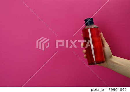 Female hand holds shower gel on pink background 79904842
