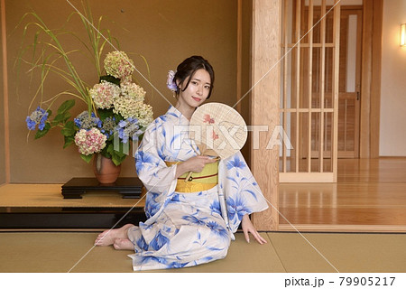 畳に座り団扇を手にくつろぐ浴衣姿の若い女性 畳に座り団扇を手にくつろぐ浴衣姿の若い女性 79905217