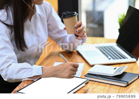 Businesswoman drinking coffee and making note on notebook. Businesswoman drinking coffee and making note on notebook. 79905699