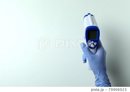 Hand in glove hold thermometer gun on white background Hand in glove hold thermometer gun on white background 79906023