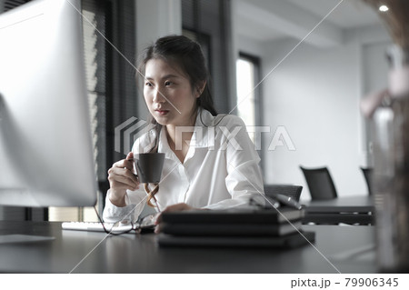 Businesswoman is watching online webinar with startup project on computer pc while drinking coffee at office. 79906345