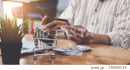 A Man holding credit card and typing in credit card number smartphone for online shopping and payment makes a purchase on the Internet. A Man holding credit card and typing in credit card number smartphone for online shopping and payment makes a purchase on the Internet. 79908534