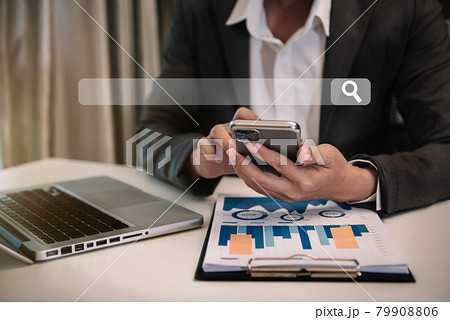 Business man uses his mobile phone to search for information he needs in his office. 79908806