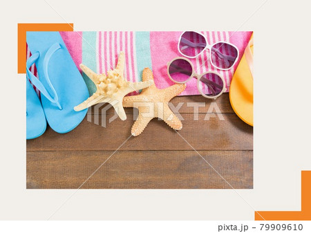 Photograph of flip flops, sunglasses and starfish on wooden surface against grey background 79909610