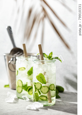 Summer sparklers, cucumber iced cocktail, hard light and shadows and tropical palm leaf 79910331