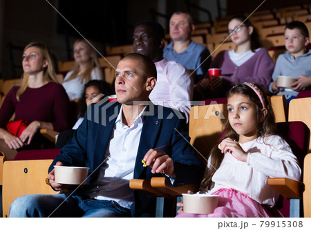 Father and tween daughter watching film together in cinema Father and tween daughter watching film together in cinema 79915308