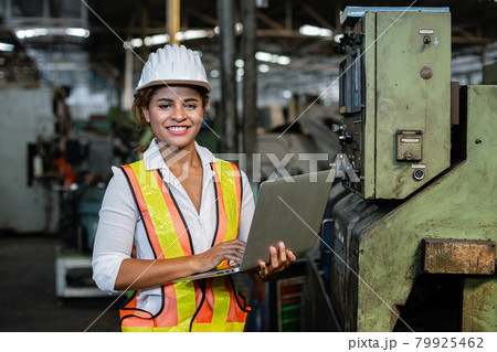 African American woman uniforms safety hardhat checking system machines with laptop in the factory. African American woman uniforms safety hardhat checking system machines with laptop in the factory. 79925462