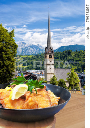 Traditional Austrian gastronomy( Schnitzel) against Bischofshofen with castle in Austria Traditional Austrian gastronomy( Schnitzel) against Bischofshofen with castle in Austria 79928867