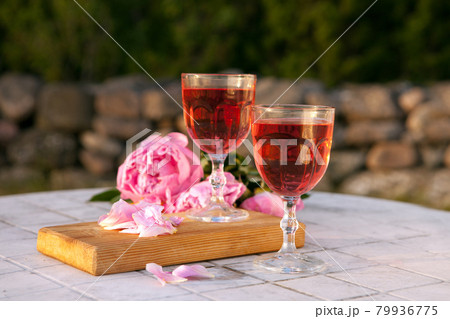 two glasses with rose wine and pink peony bouquet. delicious refreshing drink, huge blossoming flowers at the table 79936775