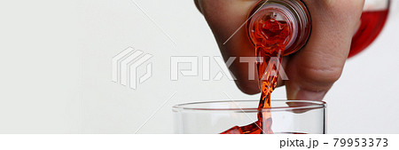 Man pouring orange drink into glass with ice closeup Man pouring orange drink into glass with ice closeup 79953373