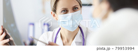 Doctor in protective mask showing patient X ray 79953994