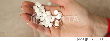 Many white pills and wedding ring lying on womans hand closeup Many white pills and wedding ring lying on womans hand closeup 79954180
