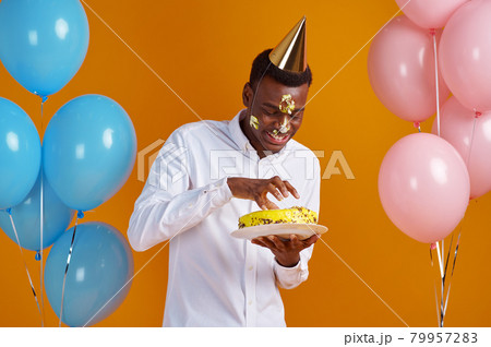 Man in cap with smeared face tasting birthday cake Man in cap with smeared face tasting birthday cake 79957283
