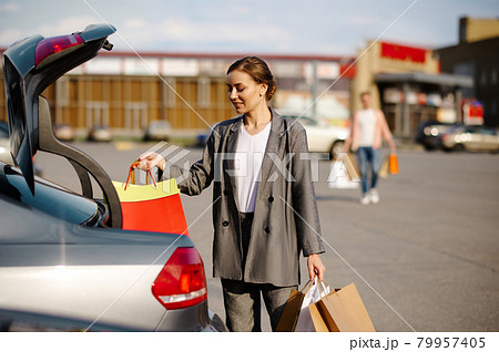 Woman puts her purchases in the trunk on parking 79957405