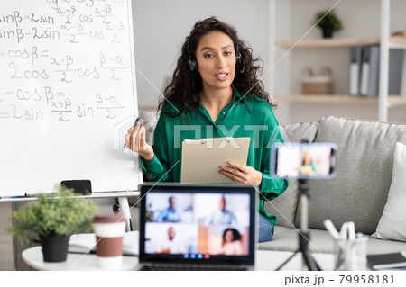 Female teacher in headset explaining math to students online Female teacher in headset explaining math to students online 79958181