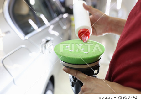 Male polisher applies protective wax to car polishing machine 79958742