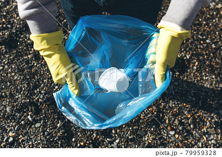 A man volunteer collects garbage on a dirty beach. The concept of waste recycling, environmental cleaning A man volunteer collects garbage on a dirty beach. The concept of waste recycling, environmental cleaning 79959328