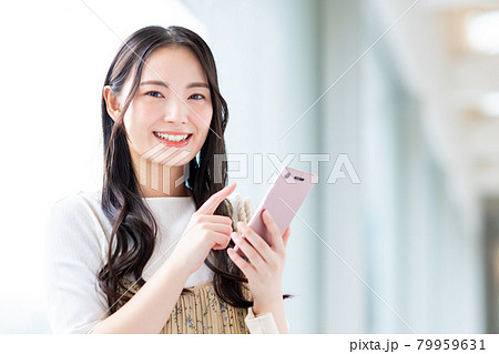 スマホを使う大学生の女の子の写真素材