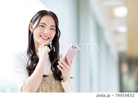 スマホを使う大学生の女の子の写真素材