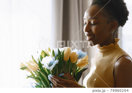 African girl with a bouquet of flowers by window African girl with a bouquet of flowers by window 79960204