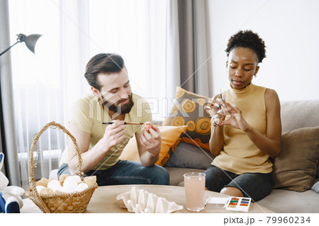 African woman and caucasian man paint easter eggs African woman and caucasian man paint easter eggs 79960234