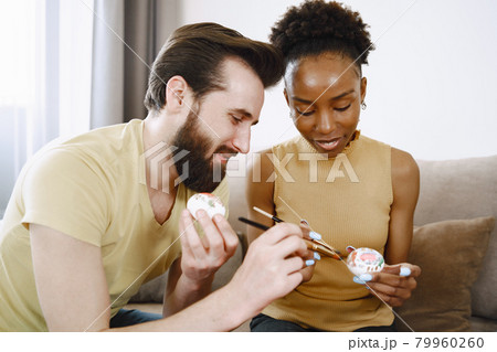 African woman and caucasian man paint easter eggs African woman and caucasian man paint easter eggs 79960260