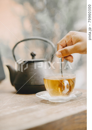 Close up shot of hand with a tea-spoon in a cup of tea. 79960300