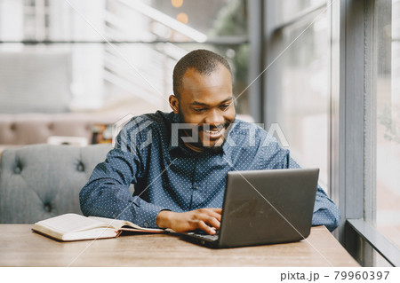 Man working behind a laptop writing in a notebook, cafe Man working behind a laptop writing in a notebook, cafe 79960397