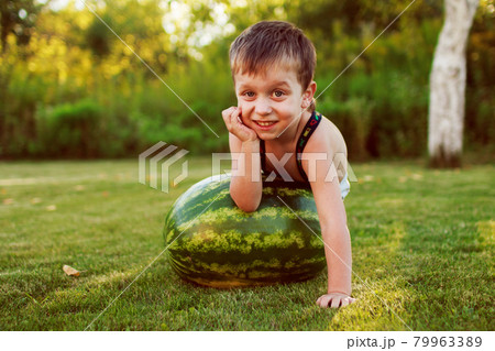 portrait of happy child boy with a large whole watermelon in the back yard 79963389