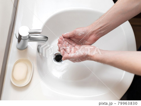 Hand washing. The man carefully washes his hands with soap. Personal hygiene. 79963830