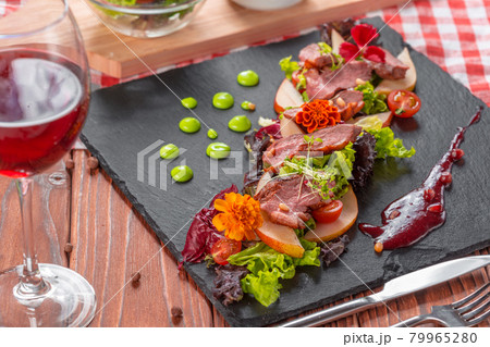 Tasty sliced roast duck breast with fresh vegetable salad closeup on a plate. Tasty sliced roast duck breast with fresh vegetable salad closeup on a plate. 79965280