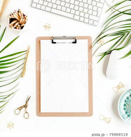 Flat lay home office desk. Female workspace with computer, clipboard, tropical palm leaves, accessories on white background. Top view.  79966519