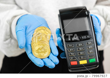 Bitcoin coins and pos terminal in woman hands in rubber gloves. Bitcoin coins and pos terminal in woman hands in rubber gloves. 79967927