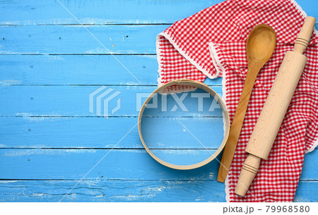 wooden rolling pin, round wooden sieve on blue background with red napkin 79968580