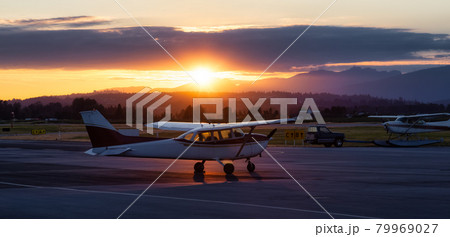 Airplanes parked at an Airport during a colorful summer sunset. Airplanes parked at an Airport during a colorful summer sunset. 79969027