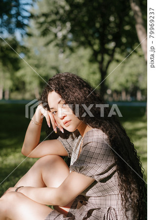 Young beautiful asian female sitting on the grass in a park Young beautiful asian female sitting on the grass in a park 79969237