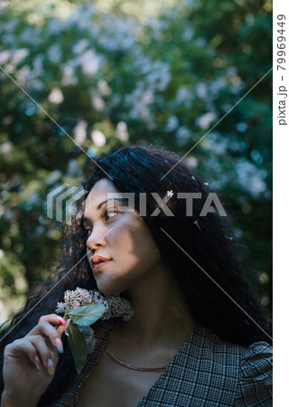 Beautiful asian female standing in front of blossom trees with flowers in her hand 79969449