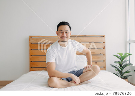 Happy man chilling and relaxed on his bed. Concept of a healthy mind. 79976320
